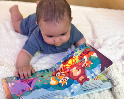 Baby lying on a fluffy white surface with a pirouette kids musical book

